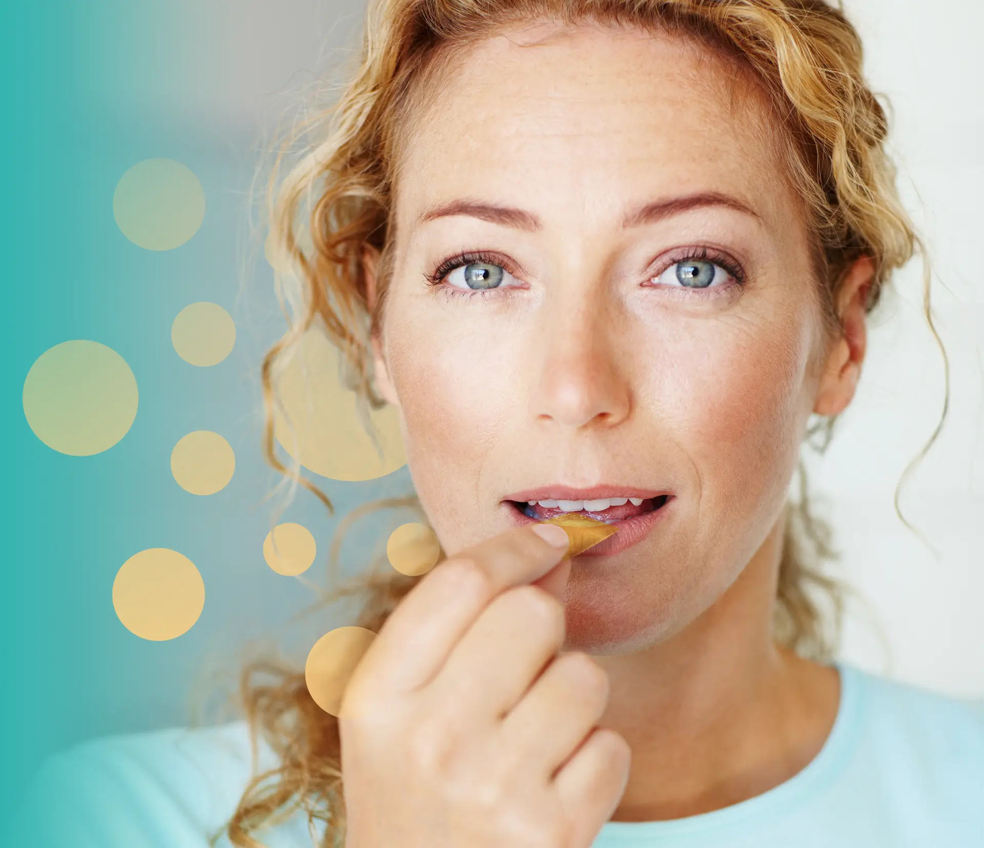 A close-up of a person with blonde curly hair placing a thin strip on their tongue against a teal and yellow dotted background.