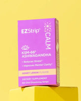 A purple EZStrip Calm supplement box with ashwagandha, placed on a yellow platform with a vibrant background.
