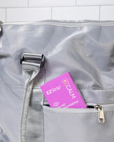 A purple EZStrip Calm box partially tucked into the front pocket of a gray travel bag.