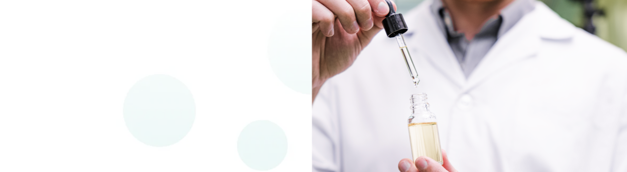 A person in a white lab coat is holding a dropper with a glass container, apparently administering liquid from the dropper into a small vial or test tube containing a light yellow solution. Only their hands and part of their torso are visible. The left side of the image has a light mint green circular design element on a white background.