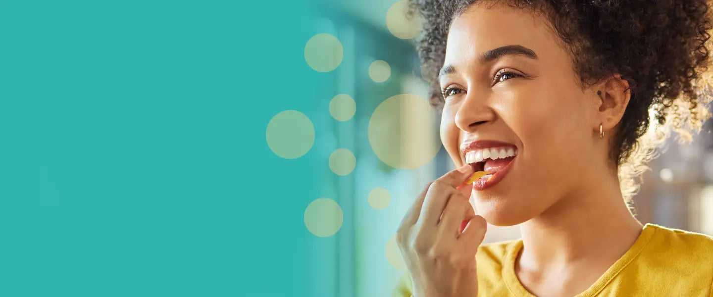 A young woman with curly hair and a bright smile placing an EZStrip oral dissolving strip in her mouth, with a teal background and glowing circular effects.
